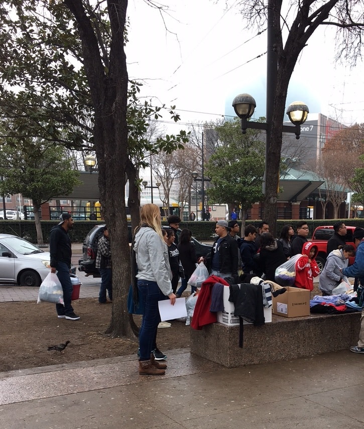 woman hands out clothing for coat drive